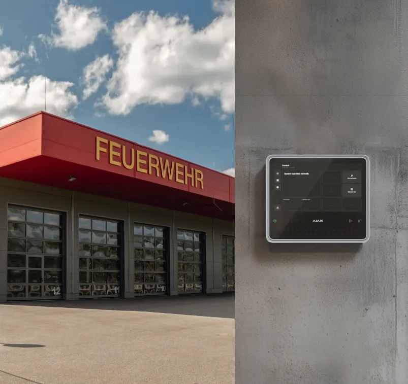 Feuerwehrhaus mit roter Fassade und Fahrzeughallen, daneben das an einer Betonwand montierte Bedienpanel der Ajax-Brandmeldeanlage